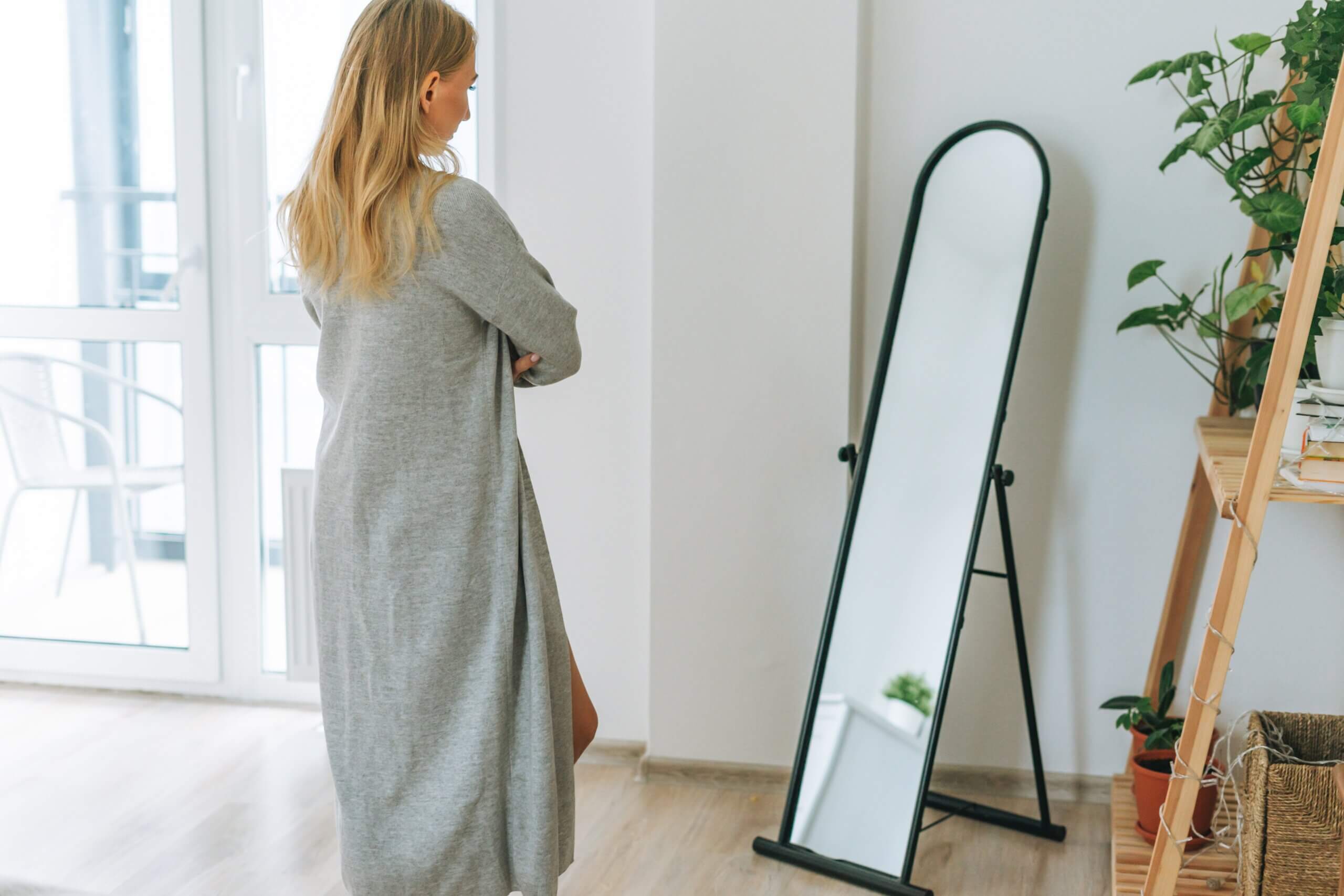 Woman reflecting and contemplating looking herself in the mirror
