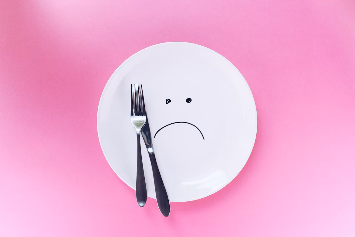 Plate with silver fork and knife and a sad face